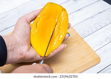 Cutting mango fruit on the wooden cutting board. Step by step instruction. - Powered by Shutterstock