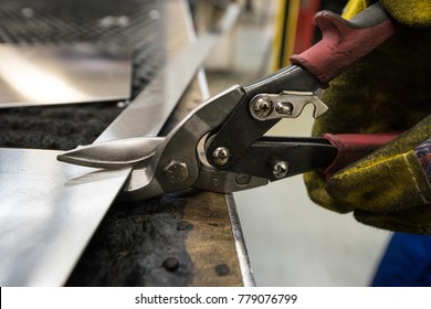 Cutting of metal sheets with powerful industrial hand-operated scissors in the shop of the plant for the production of body elements of subway cars