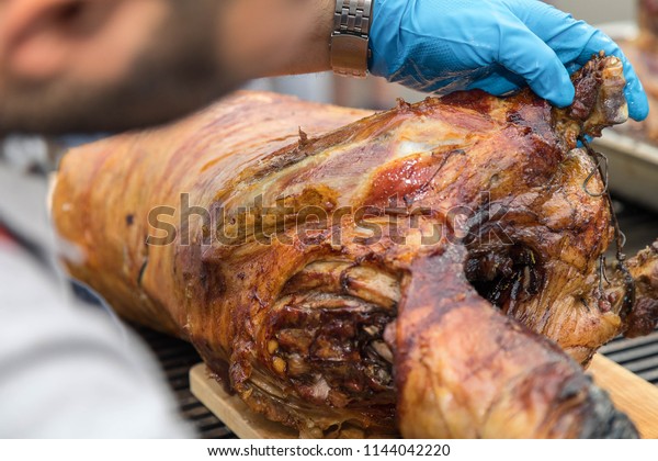  Cutting the\
mutton hulk fried on a grill for the Uzbek pilaf. Male hands keep a\
knife in gloves and cut meat