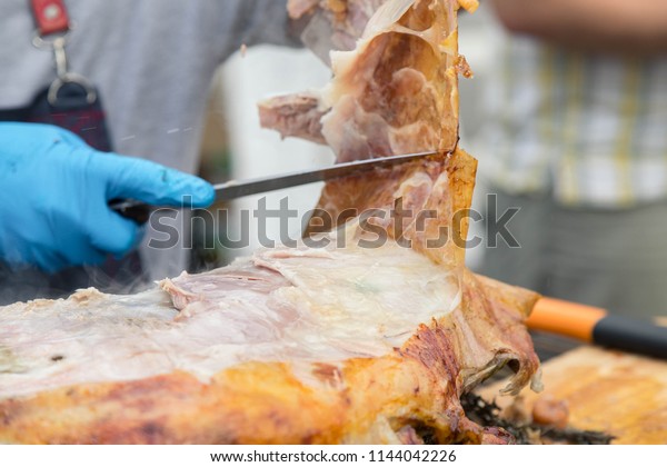  Cutting the\
mutton hulk fried on a grill for the Uzbek pilaf. Male hands keep a\
knife in gloves and cut meat