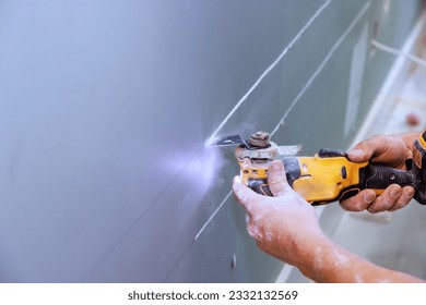Cutting plasterboard with using multi tool for laying an electric cable in wall