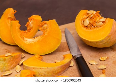 Cutting Pumpkin Wedges On Wooden Board. Cooking Healthy Vegetarian Food At Home