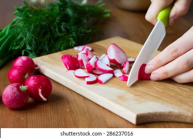 Cutting A Radish With A White Ceramic Knife