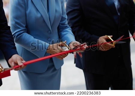 cutting a red ribbon by an adult aristocratic woman.