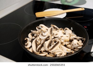 Cutting slicing champignon mushrooms, cooking with stirring fried onion  in skillet, frying pan  on induction stove. 	 - Powered by Shutterstock