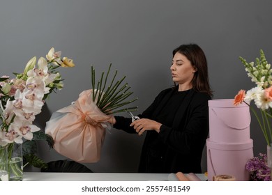 Cutting the stalk of flowers with the scissors in the flower shop. Plant care by florist. Trimming stalks of the flower arrangement to the order - Powered by Shutterstock