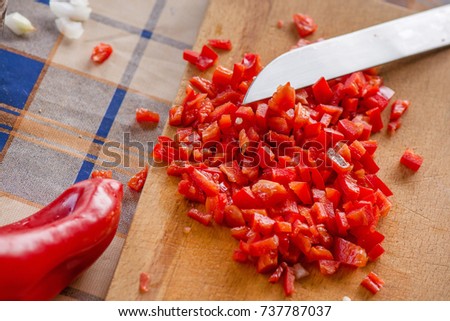 Cutting sweet red paprika and onions on wooden cutting board. Barbecue party in garden on weekend. Preparing fresh and healthy food for dinner.