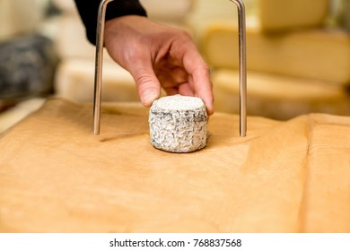 Cutting with wire slicer a young goat cheese at the food store. Close-up view - Powered by Shutterstock