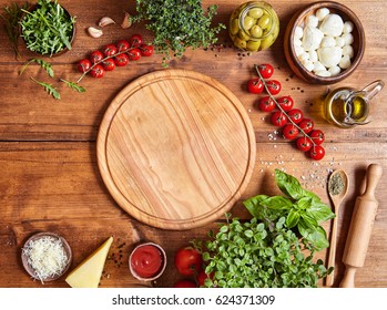 Holzbrett mit traditionellen Pizzazubereitungen: Mozzarella, Tomatensoße, Basilikum, Olivenöl, Käse, Gewürze. Holzstrukturhintergrund