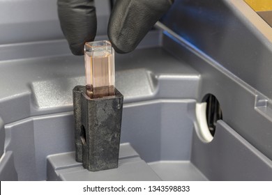 Cuvette containing a sample being placed into a spectrophotometer. 