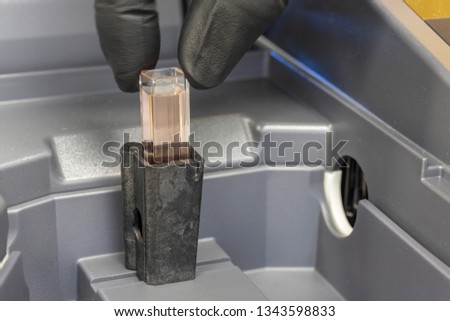 Cuvette containing a sample being placed into a spectrophotometer. 
