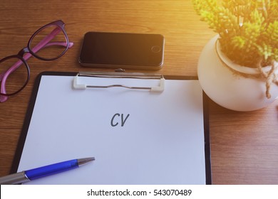 CV Word Written On Paper With Glass, Smartphone And Green Plant, Copyspace Area