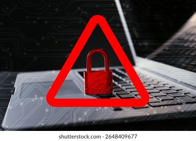 Cyber attack alert notification. Red warning sign with padlock and circuit board pattern. Laptop on table, closeup