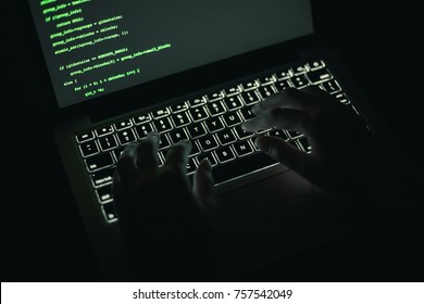 Cyber Crime Concept: Hands Of A Person Hacking On Laptop In The Darkness