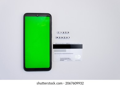 Cyber monday lettering with smartphone with green screen and payment card on white background. Online shopping concept. Chroma key. Mock up.