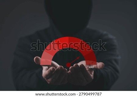 Cyber risk level indicator at maximum with hooded hacker background, representing high security threat, data breach danger, cyber attack, and digital vulnerability in technology and network systems.