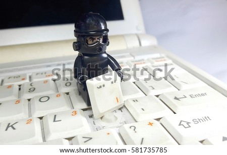 Cyber security and computer technology concept. Tiny toy figurine stealing a button on keyboard