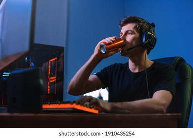 Cyber Sport. Professional Cybersport Player Training Or Playing Online Video Game On His PC Late At Night, Drinking Caffeine Energy Drink To Concentrate, Focus On Game. Team Play. Games Addiction