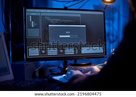 cybercrime, hacking and technology concept - close up of male hacker in dark room writing code or using computer virus program for cyber attack