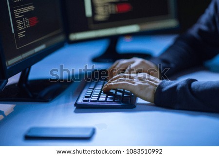 cybercrime, hacking and technology concept - hands of hacker in dark room writing code or using computer virus program for cyber attack