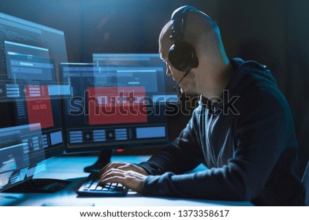 cybercrime, hacking and technology concept - male hacker in headset with access denied messages on computer's screens wiretapping or using computer virus program for cyber attack in dark room