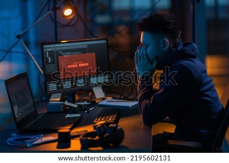 cybercrime, hacking and technology concept - male hacker in dark room using computer virus program for cyber attack