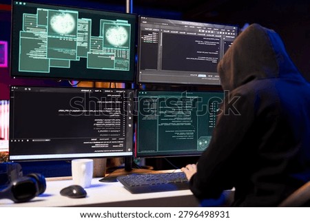 Cybercriminal coding on PC, creating stealth malware that evades security software while hacker using programming language on computer to make script hiding malicious code from detection systems.
