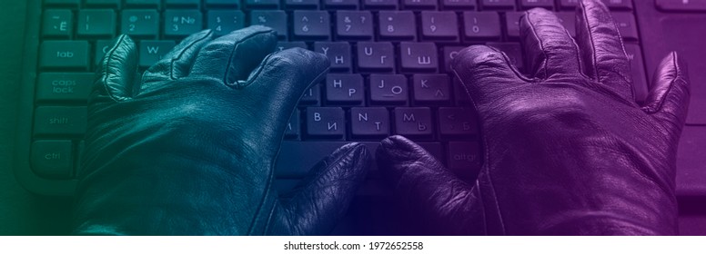 Cybercriminal, hands in gloves on laptop keyboard, photo toned in neon light. - Powered by Shutterstock