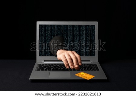A cybercriminal reaching through a laptop to steal an online shopper's credit card. Internet scams 