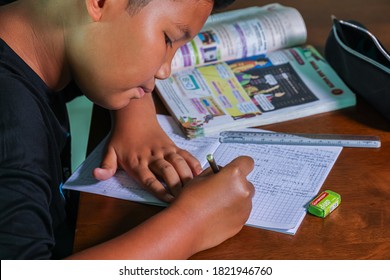 Cyberjaya, Selangor, Malaysia - September 23, 2020: Home schooling in Malaysia. Due to the corona crisis, young boy do school task at home. Teenager student works on mathematic task on a wooden desk