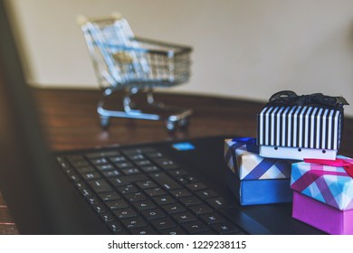 Cybermonday And Blackfriday Shopping Online. Some Gifts On A Laptop Keyboard With A Trolley On The Background. E-commerce Sale Concept.