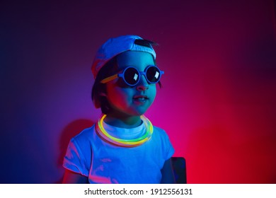 Cyberpunk Boy Child In A White T Shirt And Sunglasses Neon Sticks On The Neck Listening To Music On The Background Of The Wall