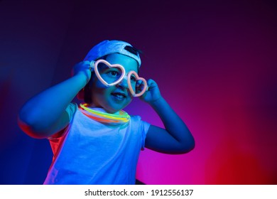 Cyberpunk Boy Child In A White T Shirt And Sunglasses Neon Sticks On The Neck Listening To Music On The Background Of The Wall