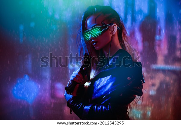 Cyberpunk concept. A courageous
cyberpunk girl warrior stands with a gun in her hands against the
backdrop of the night city of the future. Game, virtual reality.
