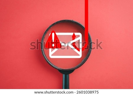 Cybersecurity alert,fraud detection, IT security, data protection,Email phishing concept.,Magnifying glass highlighting an email phishing icon on a red background idea for technology,business,web.