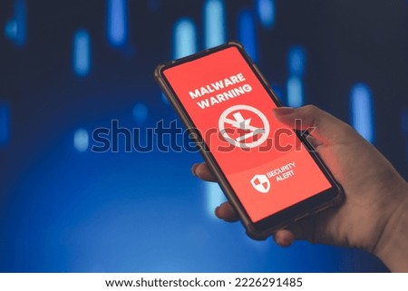 Cybersecurity concept, female hand holding a smartphone, with warning screen to be careful. Risk of downloading malware.