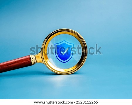 Cybersecurity, digital data and information online protection technology concept. Shield padlock icon in golden magnifying glass lens, isolated on net grid and blue background, minimal style.