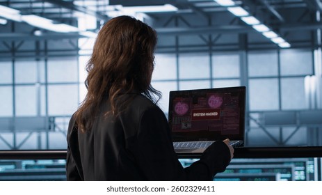 Cybersecurity expert in data center frantically trying to counter a hacker attack. Server room worker under pressure to secure sensitive information after threat alert received on laptop, camera A