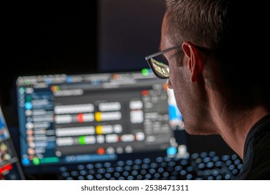 Cybersecurity Professional Analyzing Data on Multiple Screens in a Low-Light Workspace for Network Security Assessment - Powered by Shutterstock