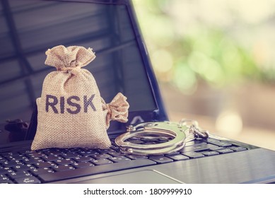 Cybersecurity Risk And Threat, Information Technology Concept : Bag With A Word RISK And A Handcuff On A Laptop Computer, Depicts Protecting Integrity, Confidentiality, Personal Data And Digital Asset