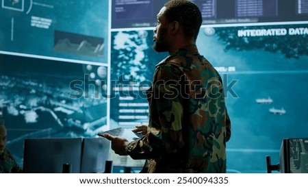 Cybersecurity specialist operates in a high tech military control center, monitoring surveillance footage and gathering intelligence for a new defense mission. Secret service activity. Camera A.