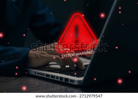 A cybersecurity warning alert appears on a laptop as a user types, symbolizing system errors, data breaches, online threats, malware risks, and digital protection in modern computer environments.