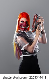 Cyborg Mercenary In Asian Demon Mask, Young Woman With Bright Orange Hair With A Gun In Her Hands, Futuristic Cyber Punk Style