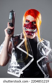 Cyborg Mercenary In Asian Demon Mask, Young Woman With Bright Orange Hair With A Gun In Her Hands, Futuristic Cyber Punk Style