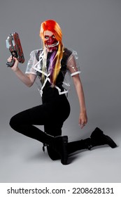 Cyborg Mercenary In Asian Demon Mask, Young Woman With Bright Orange Hair With A Gun In Her Hands, Futuristic Cyber Punk Style