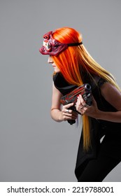 Cyborg Mercenary In Asian Demon Mask, Young Woman With Bright Orange Hair With A Gun In Her Hands, Futuristic Cyber Punk Style