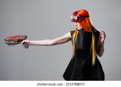 Cyborg Mercenary In Asian Demon Mask, Young Woman With Bright Orange Hair With A Gun In Her Hands, Futuristic Cyber Punk Style