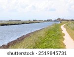 cycle path on the river bank with the lagoon in the plain in summer without people