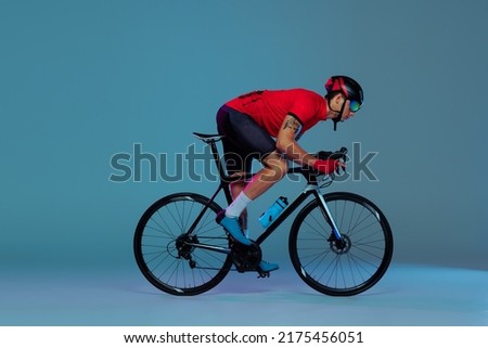 Cycle race. Studio shot of professional cyclist in red sports uniform, goggles and a helmet on a blue background. Concept of active life, rest, travel, energy, sport. Copy space for ad