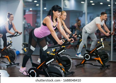 Cycling class in fitness club, group of fit people spinning on cardio machine. Man and women do sports exercises at gym fat burning class. Active lifestyle, health care and body training concept - Powered by Shutterstock